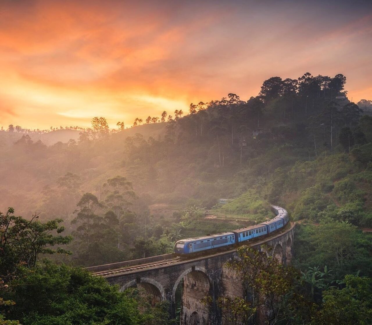 Blue train crossing Nine Arch Bridge through Ella’s green hills